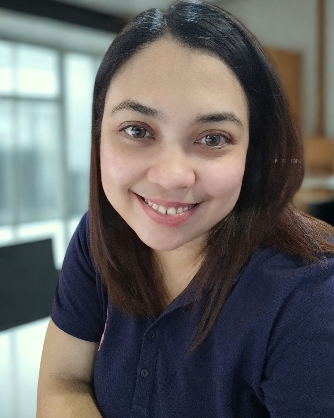 Portrait of Arianne Jane Preligera smiling indoors, wearing a navy blue shirt, with soft natural lighting.