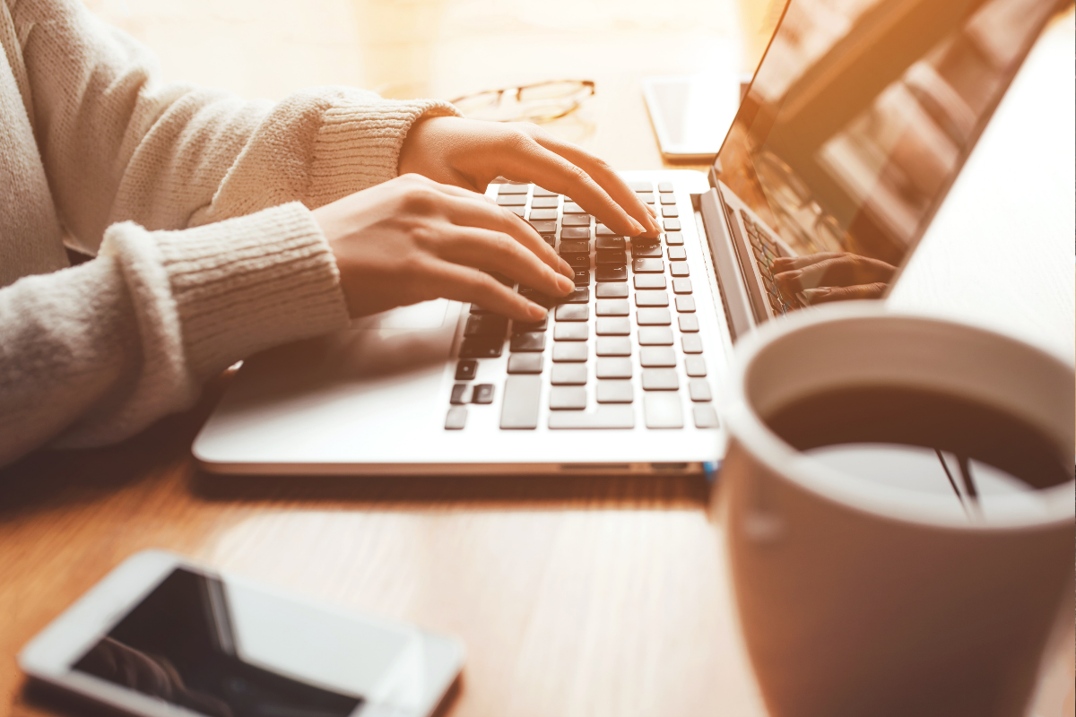 person working at desk with laptop and coffee